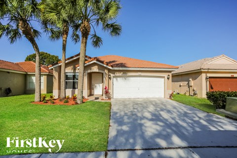 a house with a driveway and palm trees in front of it
