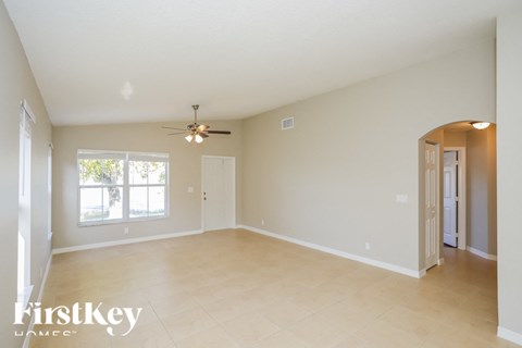 an empty living room with a ceiling fan and a window