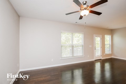 an empty living room with a ceiling fan and window