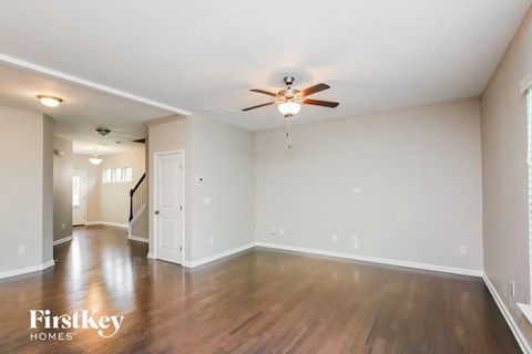 an empty living room with wood floors and a ceiling fan