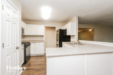 A kitchen with white cabinets and a black fridge.