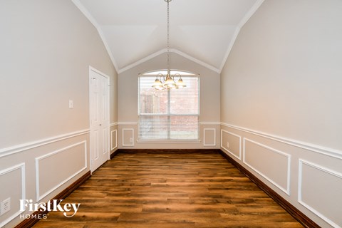 a dining room with wood floors and white walls and a window