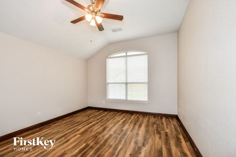 a bedroom with hardwood flooring and a ceiling fan