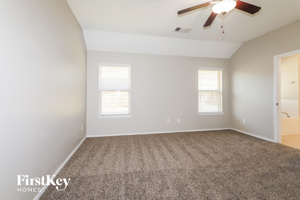 an empty living room with carpet and a ceiling fan