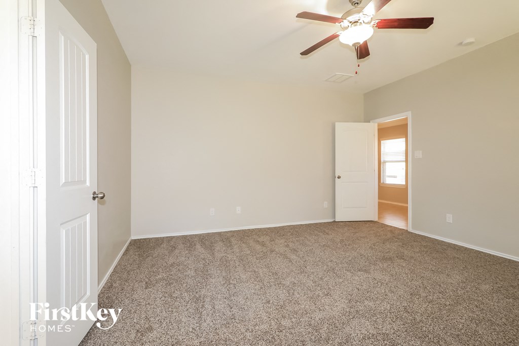 a spacious living room with carpet and a ceiling fan