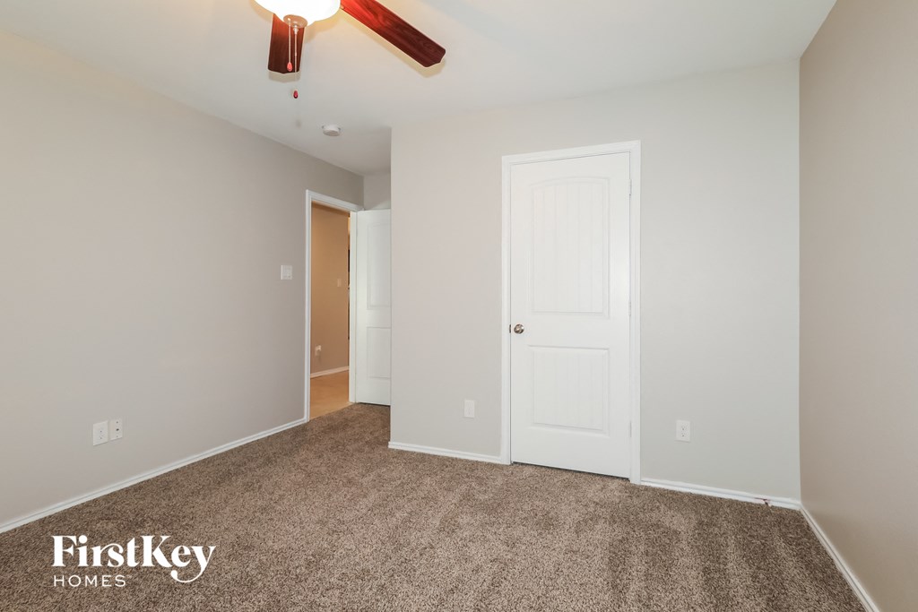 a bedroom with a white door and a ceiling fan