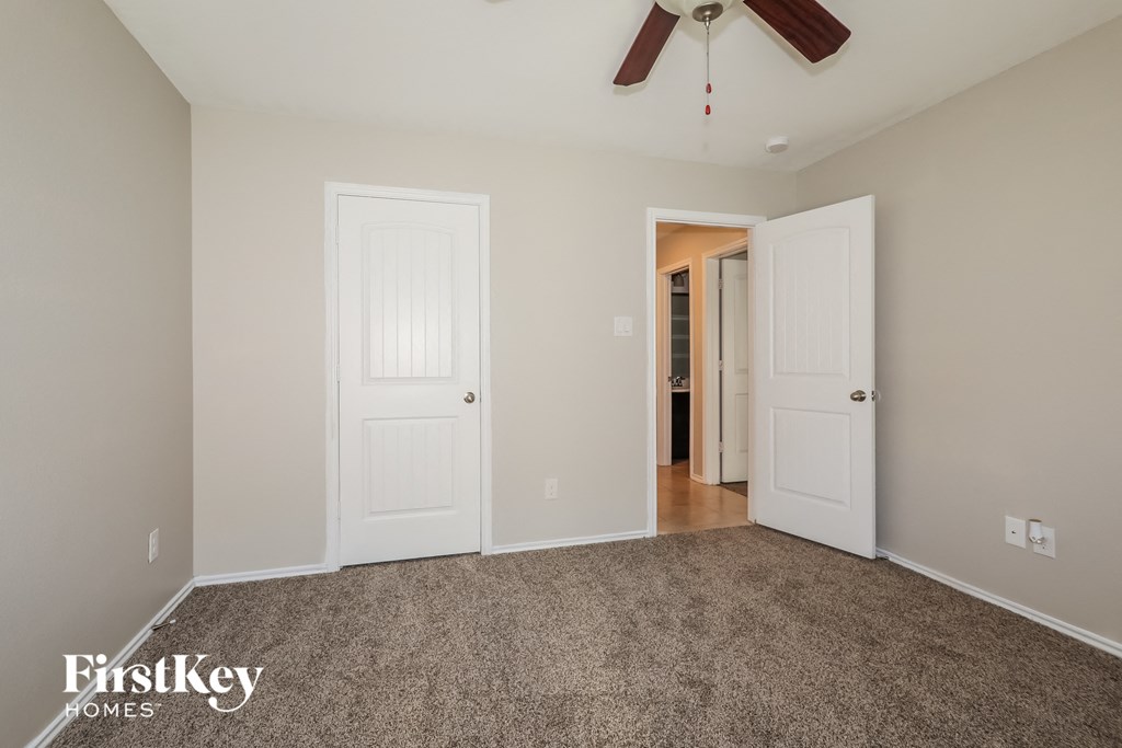 a bedroom with two doors and a ceiling fan
