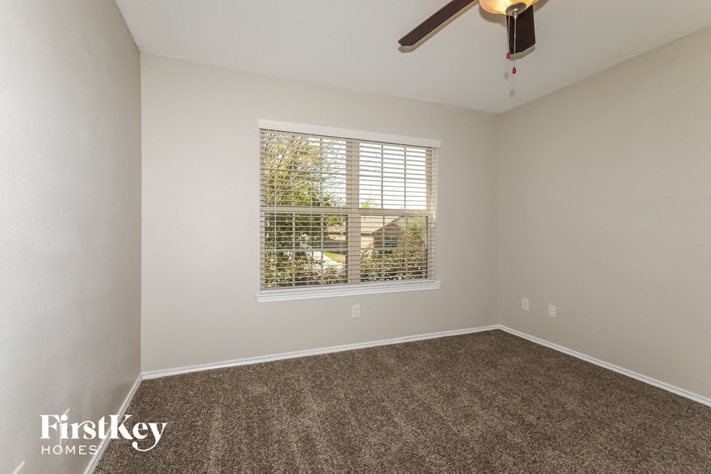 a room with carpet and a window and a ceiling fan