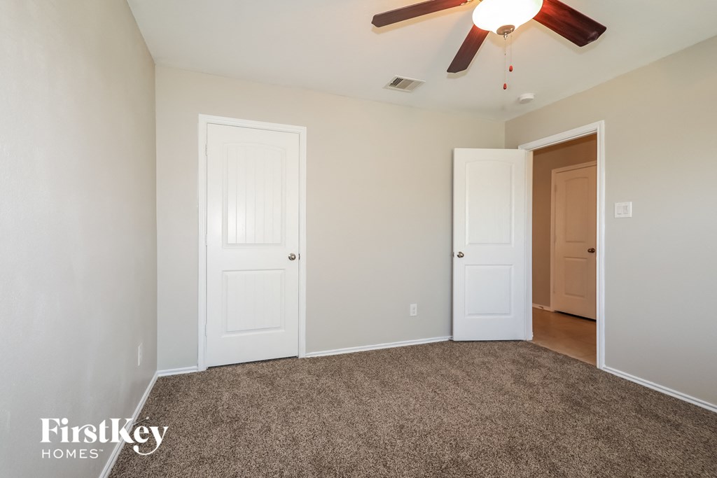 a bedroom with two doors and a ceiling fan