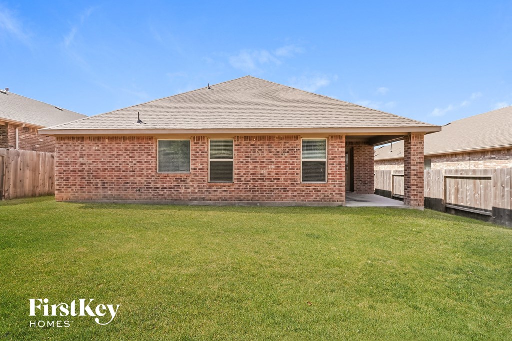 a brick house with a lawn and a wooden fence