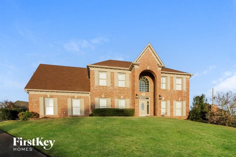 a brick house with a green lawn and a blue sky