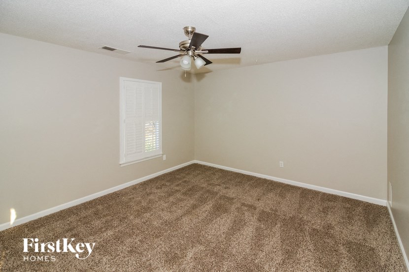 the spacious living room with carpet and a ceiling fan