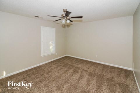the spacious living room with carpet and a ceiling fan