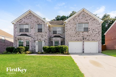 a brick house with two garage doors and a lawn