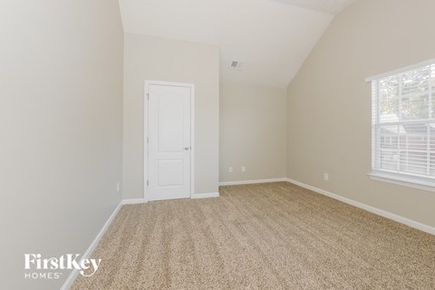 the bedroom of a home with a white door and carpet