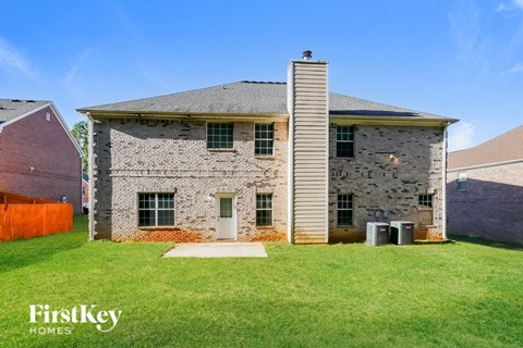 an old brick house with a grassy yard and a barn