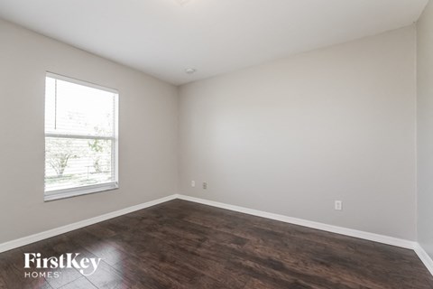 the living room of a home with wood flooring and a window