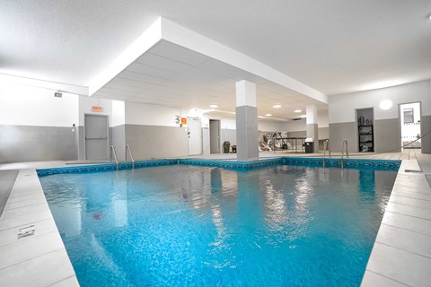 A large indoor swimming pool with a blue tinted water.