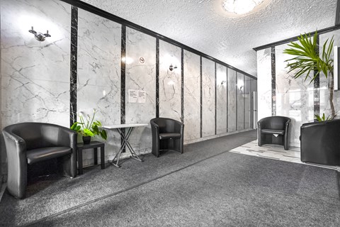 A black leather chair is in front of a marble wall.