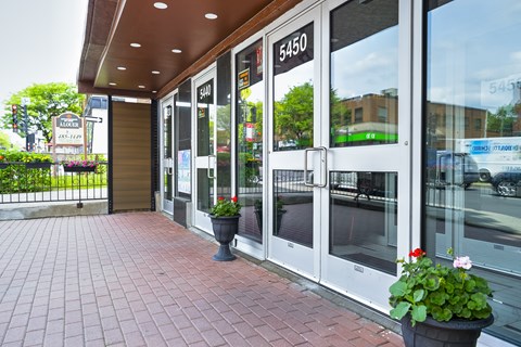The image shows a building entrance with a glass door and a sign that reads "5450".