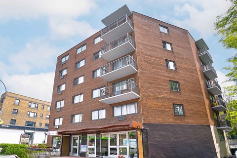 A tall apartment building with balconies on the upper floors.