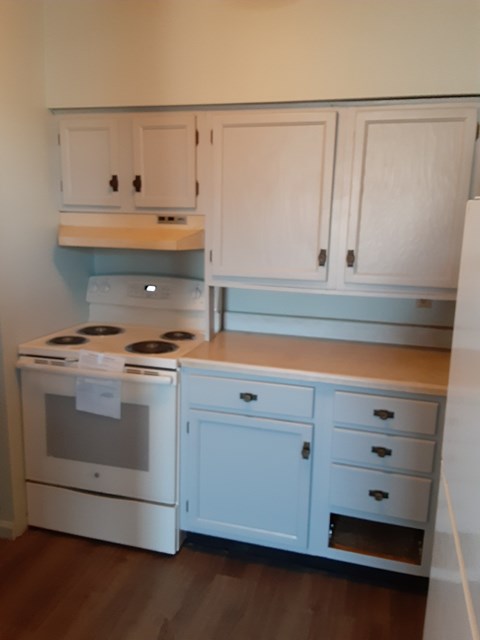 a kitchen with white cabinets and a stove and a counter