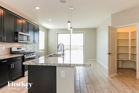 A kitchen with black cabinets and a granite countertop.