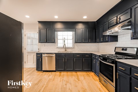 A kitchen with black cabinets and a wooden floor.