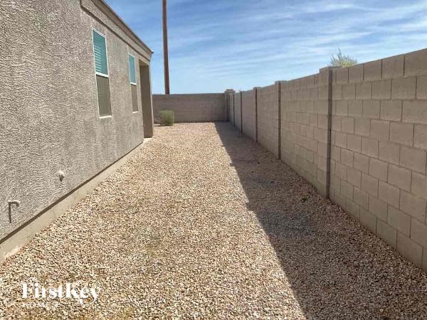 a long gravel driveway next to a brick wall