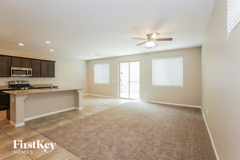 A spacious living room with a kitchen area and a carpeted floor.