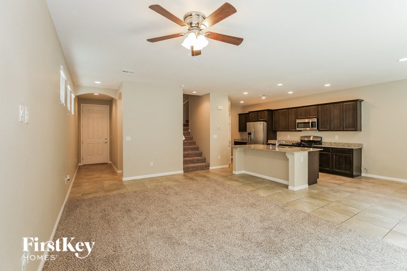 A spacious living room with a kitchen in the background.