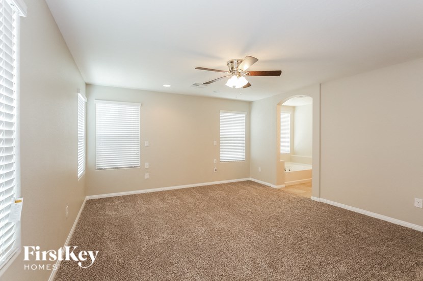 A spacious room with a ceiling fan and carpeted floor.