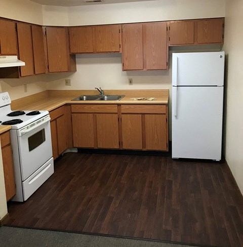 an empty kitchen with white appliances and wooden cabinets