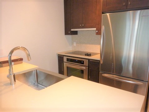 A kitchen with a stainless steel refrigerator and a sink with a faucet.