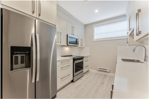 a white kitchen with stainless steel appliances and white cabinets