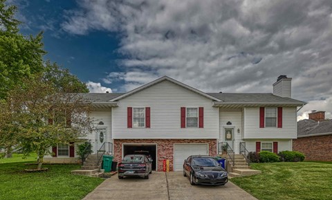 A white house with a grey car parked in front.