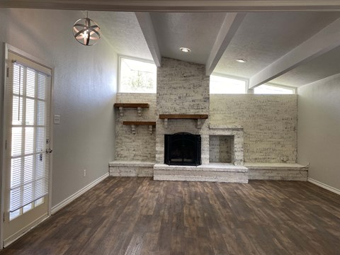 an empty living room with a fireplace and wooden floors
