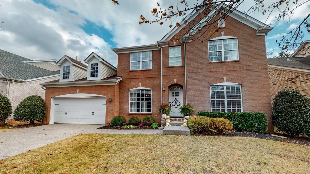 a brick house with a white garage door and a lawn