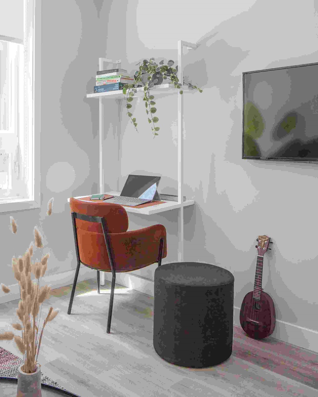 A red chair sits in front of a desk with a laptop on it.