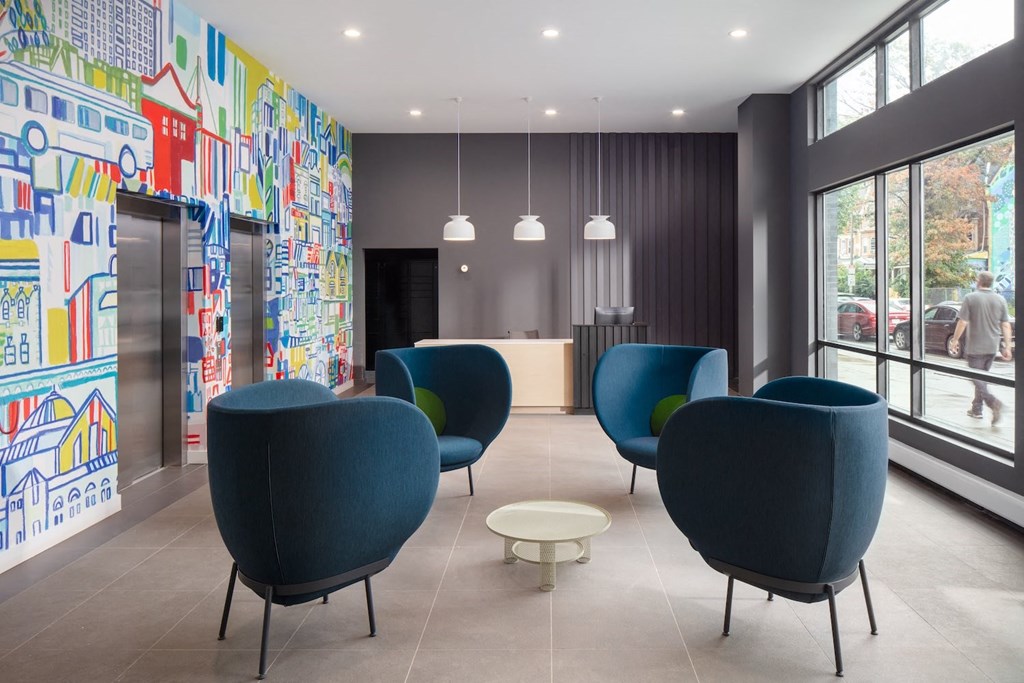 A room with blue chairs and a wall with a mural of buildings.