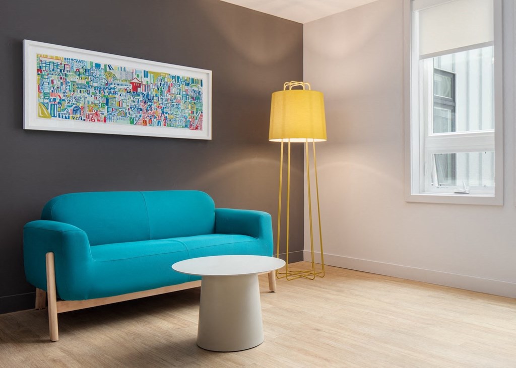 a living room with a blue couch and a yellow lamp and a table