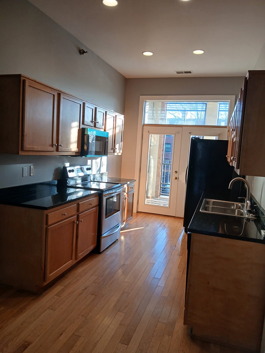 A kitchen with wooden cabinets and black countertops.