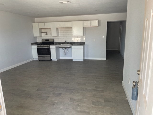 an empty kitchen with white cabinets and a sink