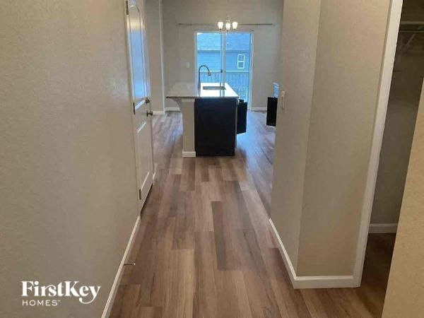 a hallway with a kitchen and wood flooring