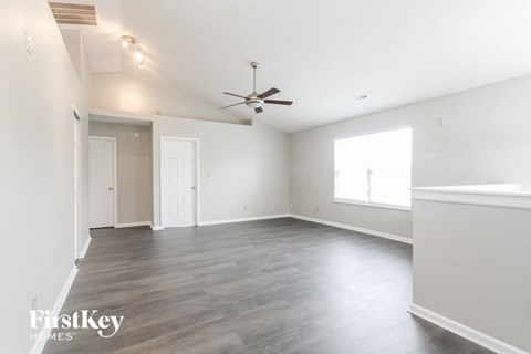 A spacious room with a ceiling fan and hardwood flooring.