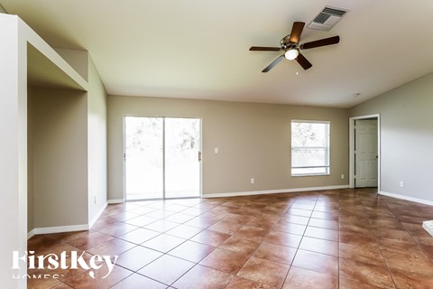 an empty living room with a ceiling fan and tiled floors