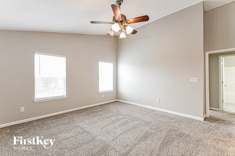 the spacious living room with ceiling fan and carpet