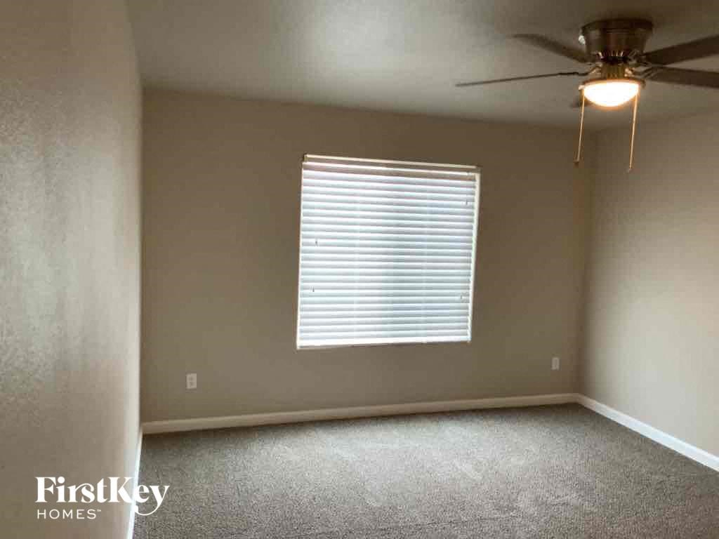 an empty living room with a window and a ceiling fan