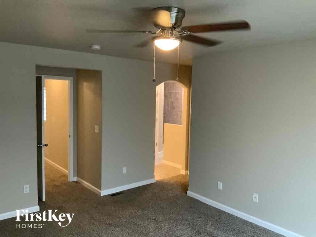 an empty living room with a ceiling fan and a closet