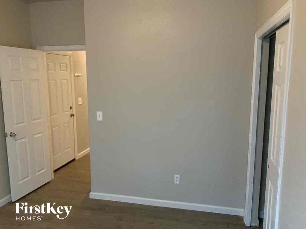 an empty hallway with a door to a bedroom and a closet